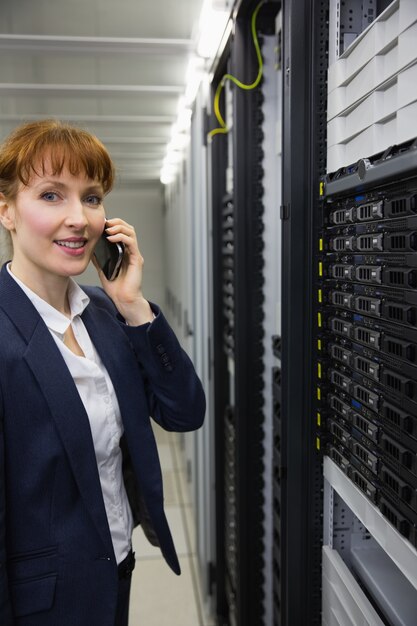 Smiling technician talking on phone while looking at server