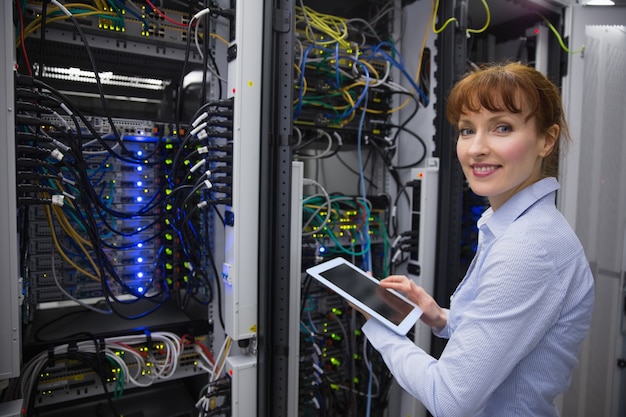 Smiling technician using tablet pc while analysing server