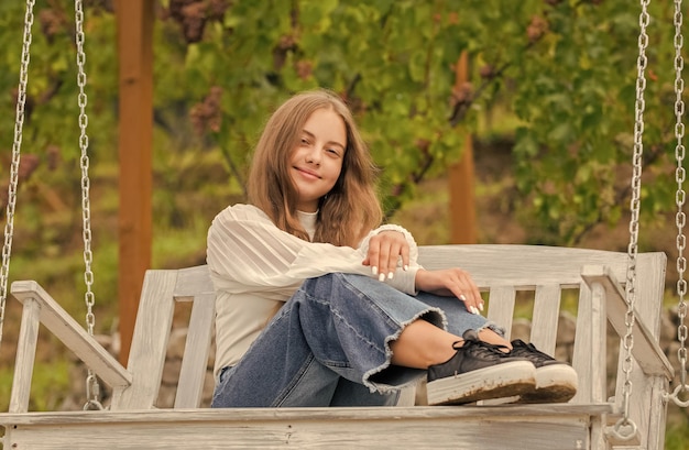 Smiling teen girl having free time outside on swing happiness