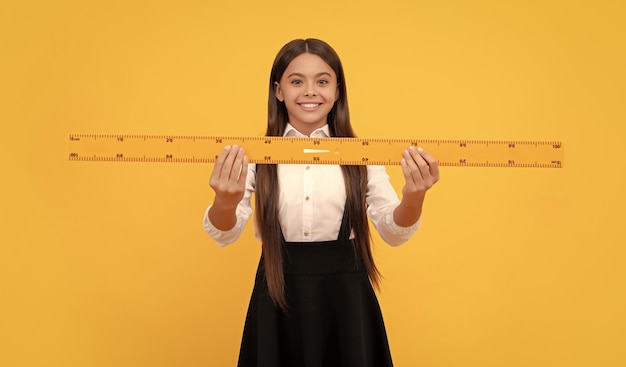 Smiling teen girl hold ruler back to school algebra and geometry kid study math