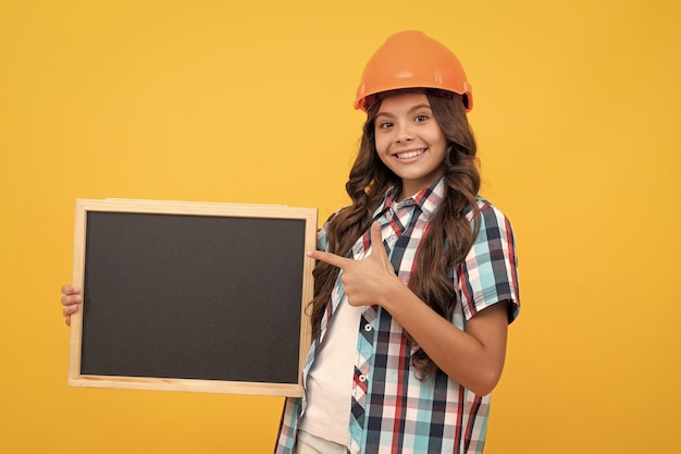 Smiling teen girl laborer pointing finger on blackboard child advertising labor day