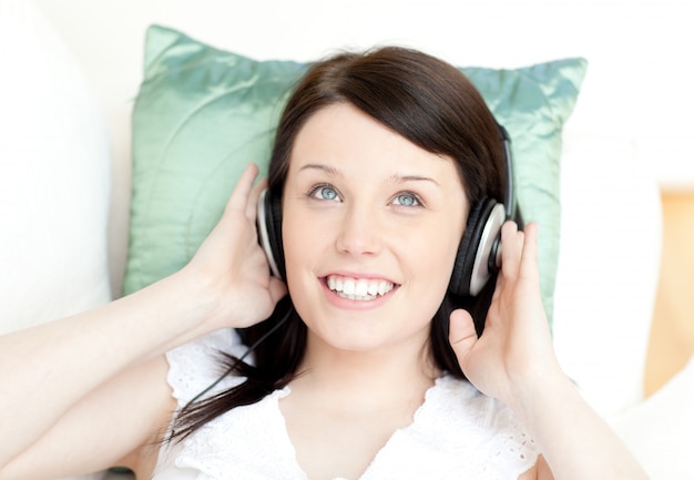 Smiling teen girl listening music lying on a sofa