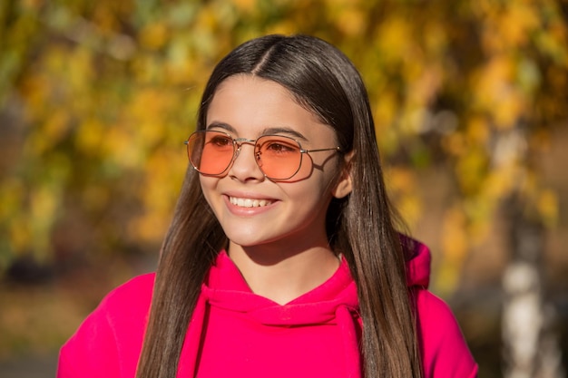 선글라스를 쓰고 가을 시즌에 야외 웃는 십대 소녀