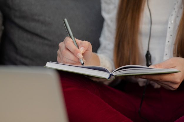 Smiling teen girl wearing headphones listening to audio course making notes, young woman learning foreign languages, digital self education, studying online, enjoying music.