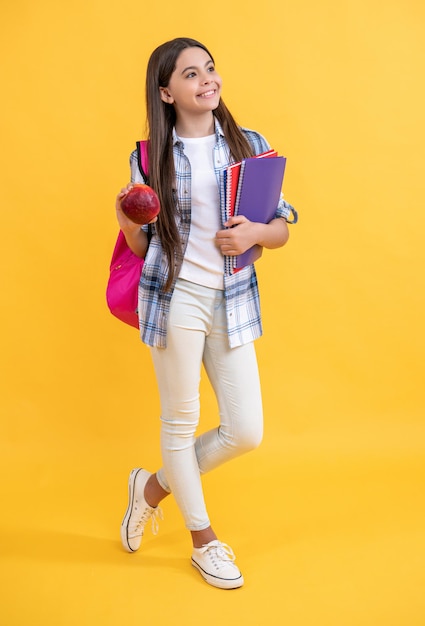 スタジオで笑顔のティーンエイジャーの学校の女の子 背景の写真 背包を背負ったティーンエアの学校の少女 黄色で孤立したティーンエージャーの女の子