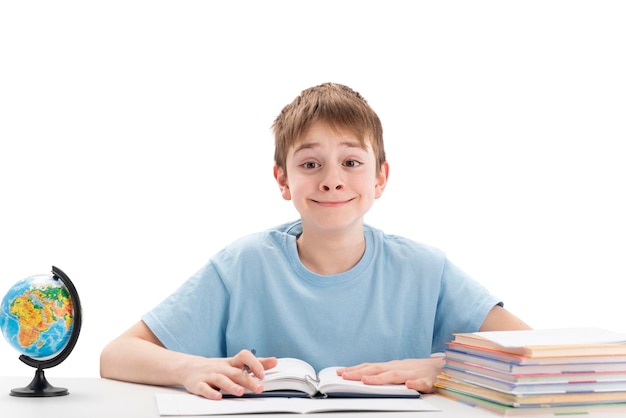 Smiling teenage boy sits at table with stack of notebooks doing homework Education abroad concept International education