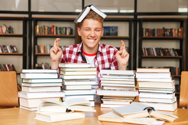 Photo smiling teenage boy sitting at the library table