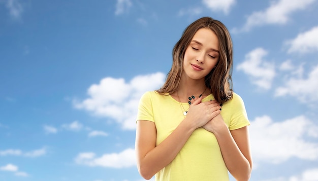 Photo smiling teenage girl holding hands on heart