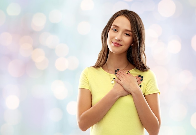 Photo smiling teenage girl holding hands on heart