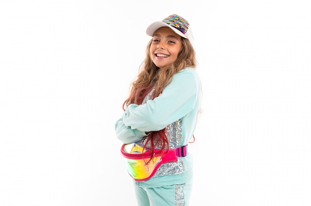 Smiling teenage girl in sparkling clothes, fashionable cap and wearing waist bag 