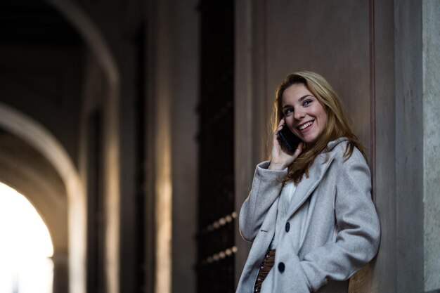 Smiling teenage girl talking with her smartphone in the street