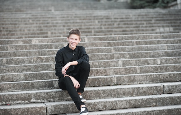 Smiling teenage student boy sit on stairs