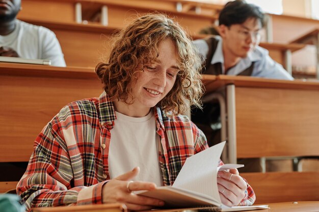 Smiling teenage student of highschool or college looking through notes