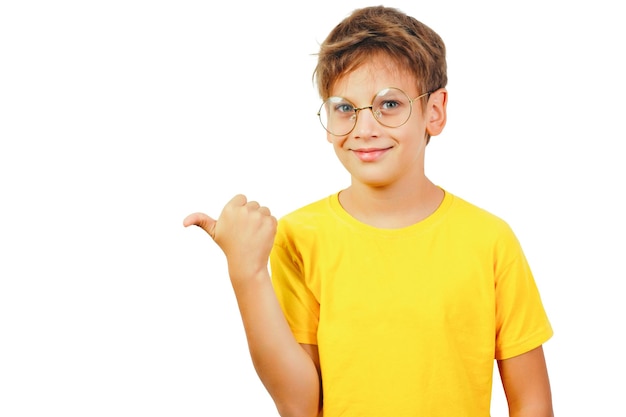 Smiling teenager in glasses and a yellow tshirt points his thumb to the left