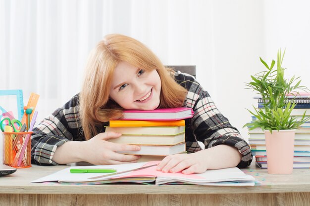 Smiling teenager student girl doing homework at home, education and school concept