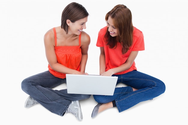 Smiling teenagers sitting cross-legged with a laptop