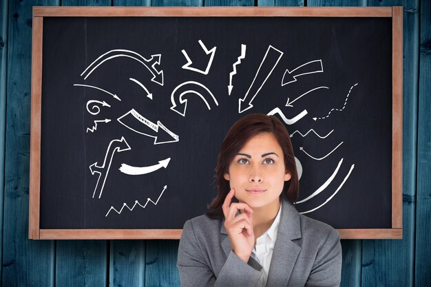 Smiling thoughtful businesswoman against chalkboard on blue wooden planks