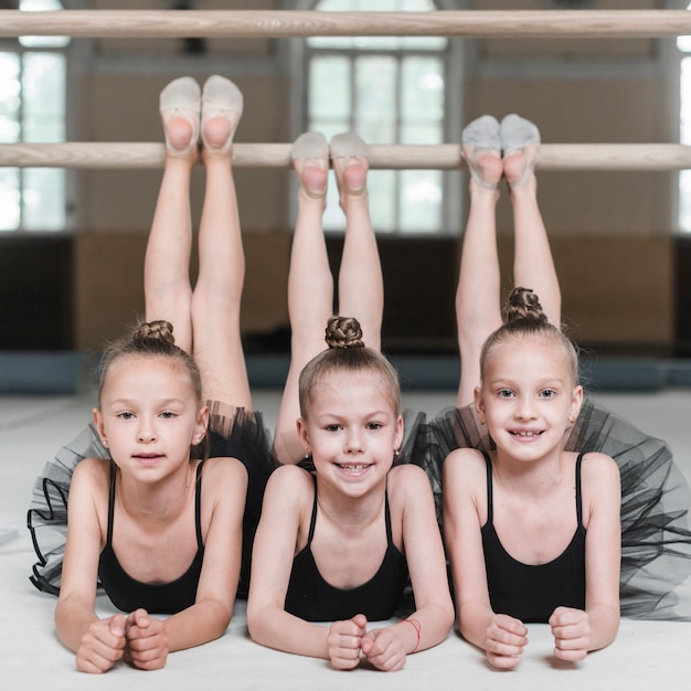 Фото Улыбаясь три девочки-балерины, растягивающие ноги на барре