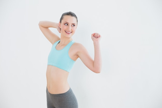 Smiling toned woman stretching hands against wall