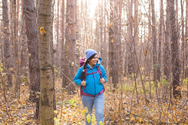 Smiling tourist woman walking with backpacks over autumn natural background.