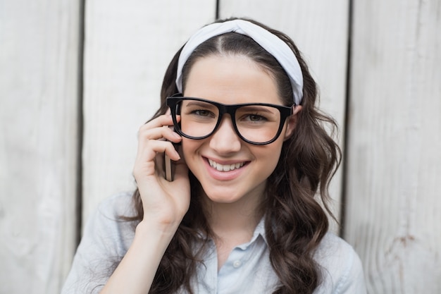 Donna alla moda sorridente con gli occhiali alla moda che hanno telefonata