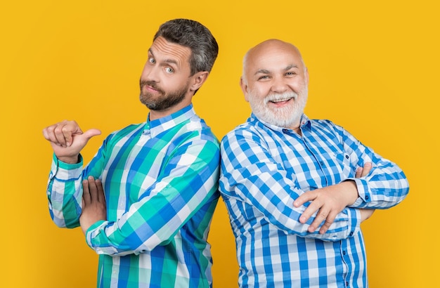 Smiling two generation family men on background photo of two generation family men wear checkered shirt two generation family men isolated on yellow two generation family men in studio