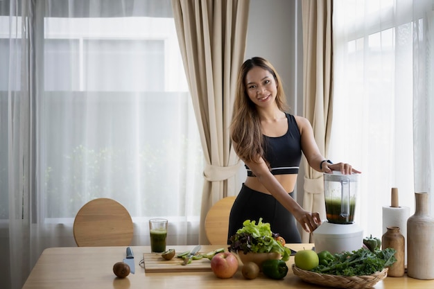 緑のデトックス野菜のスムージーを飲む笑顔の菜食主義の女性健康的なライフスタイルの概念