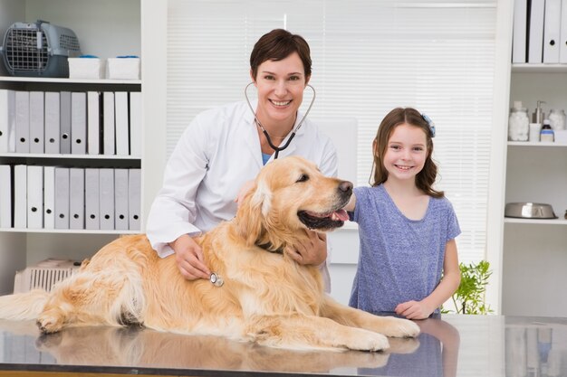 Smiling vet examining a dog with its owner