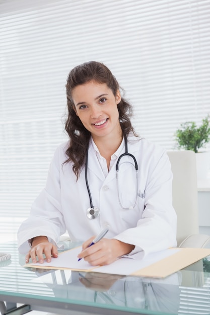 Smiling vet sitting and writing notes