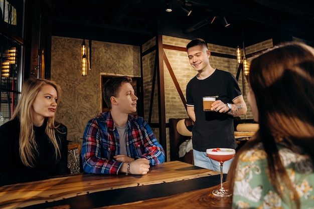 Photo smiling waiter brought the order to friends company in restaurant