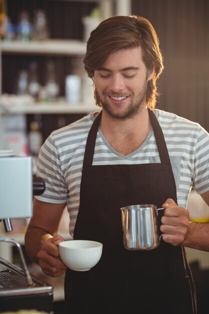 Smiling waiter making cup of coffee