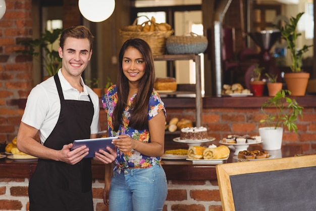 Smiling waiter and pretty customer looking on tablet