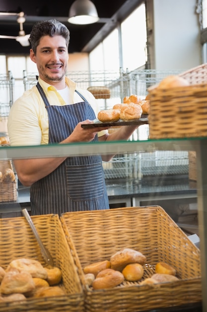 Smiling waiter showing tray of breads