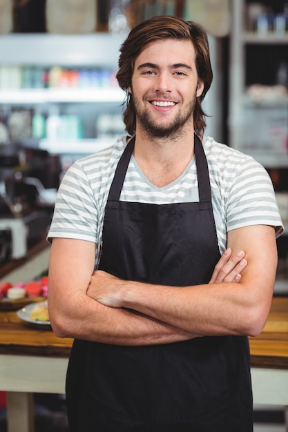  smiling waiter standing with arm crossed