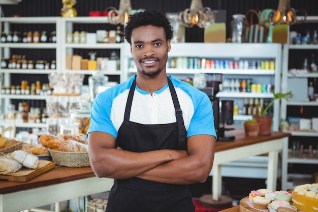 Smiling waiter standing with arms crossed