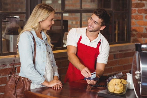 Photo smiling waiter swiping the credit card