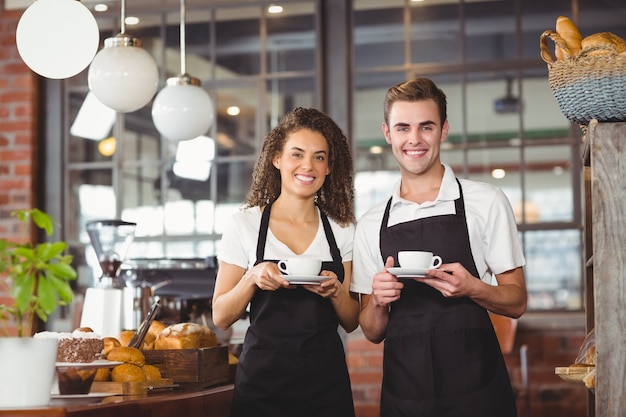 Photo smiling waiter and waitress holding cup of coffee