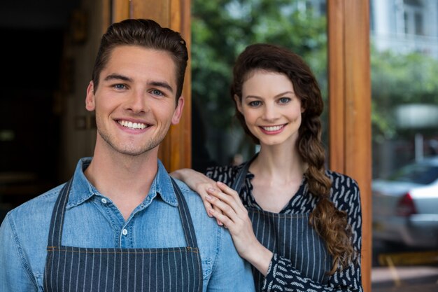 Smiling waiter and waitress standing outside the cafe