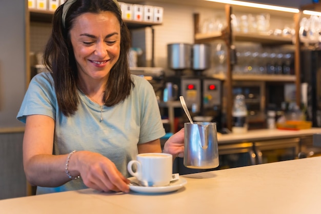 Smiling waitress in the cafeteria with the coffee prepared handing it to the client the restrictions due to covid