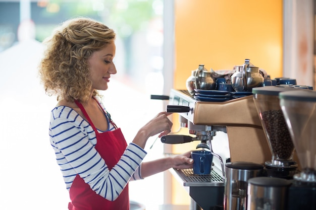 Smiling waitress making cup of coffee