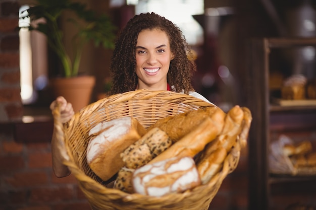 Smiling waitress showing a basket of bread