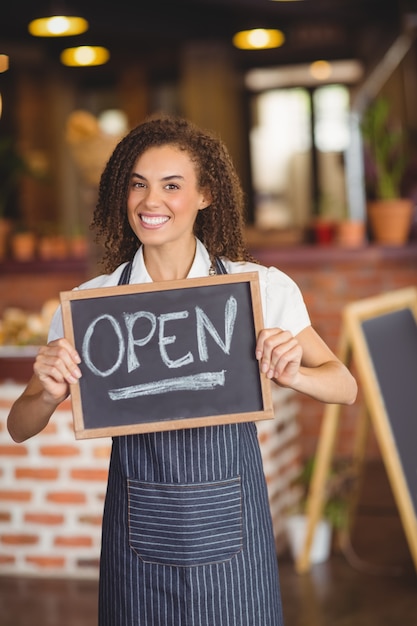 Smiling waitress showing chalkboard with open sign 