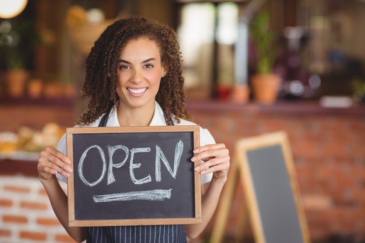 Photo smiling waitress showing chalkboard with open sign 