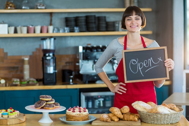 Smiling waitress showing slate with open sign