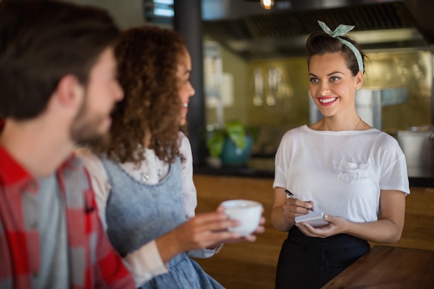 Smiling waitress taking orders in restaurant