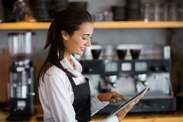Улыбающаяся официантка с помощью цифрового планшета