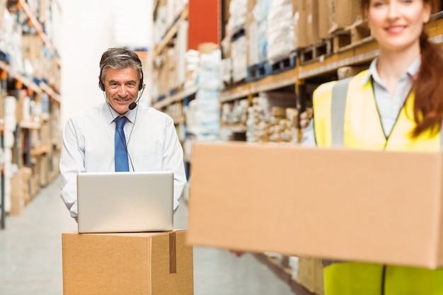 Smiling warehouse manager using laptop