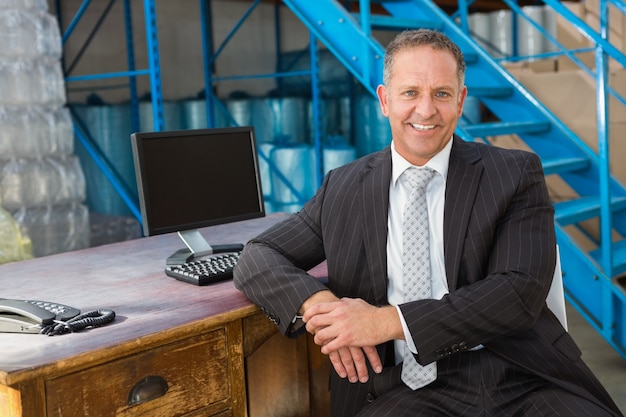 Smiling warehouse manager with computer