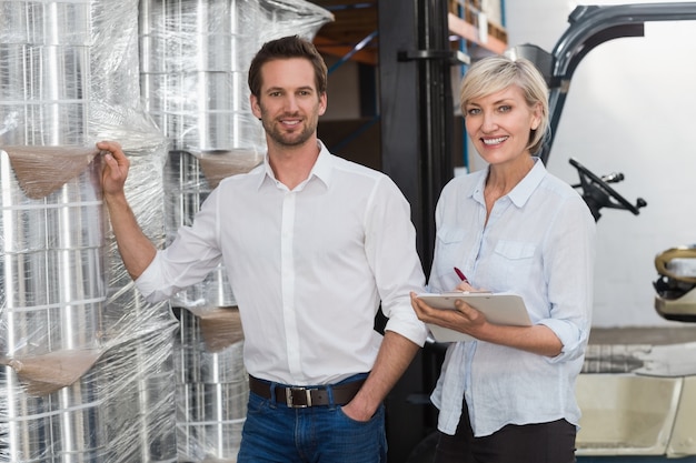 Smiling warehouse managers checking inventory