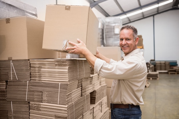 Smiling warehouse worker taking a box in a large warehouse